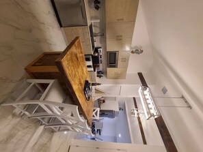 Enjoy cooking in this well-equipped kitchen with a central island, sink, and stove, complemented by a dining area with a table and chair.
