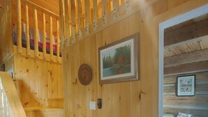 Puinen portaikko johtaa makuuhuoneeseen, jossa on sänky, seinällä on kehystetty kuva ja seinässä on myös pieni pyöreä esine.