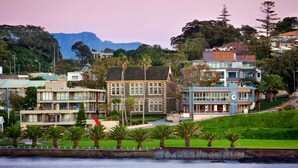 A coastal building with a prominent entrance, a flag, and a view of the sea. - Harbourside Studio Apartment (Kiama)