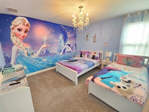 Ein Schlafzimmer mit Wandgemälde einer Figur, zwei Betten mit thematisch passender Bettwäsche, einer Kristallleuchtre und einem Fenster mit Vorhängen.