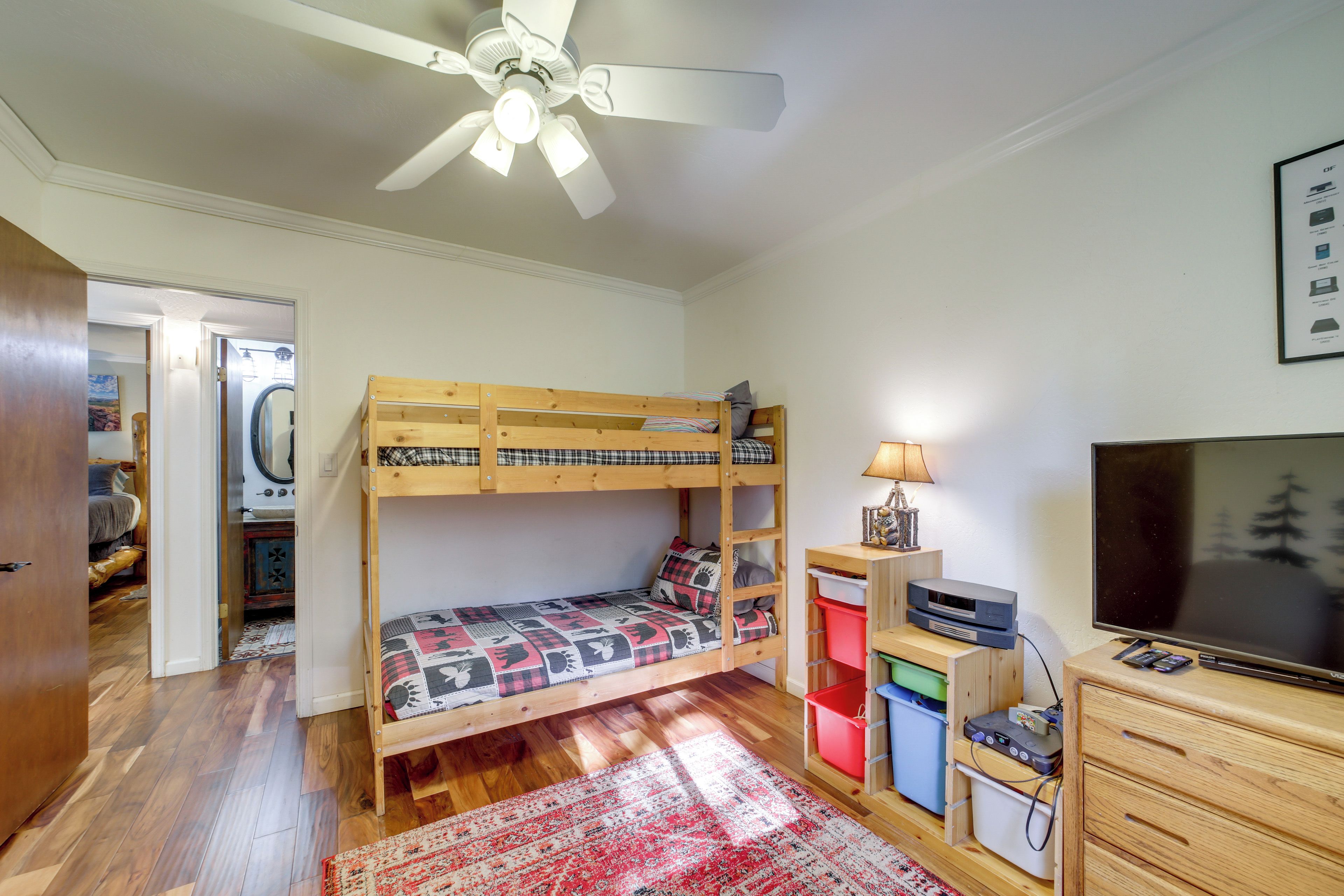 A bunk bed room with a ceiling fan, a television, and a red patterned rug.