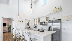 Una cocina moderna con una isla central, electrodomésticos de acero inoxidable y taburetes de bar.