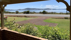 A covered outdoor area with a view of a road and a body of water. - Enjoy Sunrise Views from the comfort of this beautiful home away from home! (Little Grove)