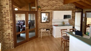 A cozy kitchen with wooden beams, a brick wall, and a large window. - Enjoy Sunrise Views from the comfort of this beautiful home away from home! (Little Grove)
