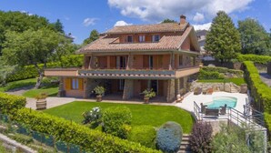 Ein zweistöckiges Haus mit Balkon, Pool und gepflegtem Garten.