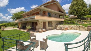 Ein zweistöckiges Haus mit Swimmingpool, Gartenmöbeln und einer Steintreppe.