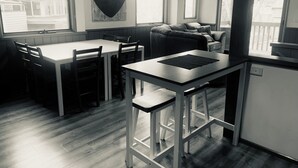 A modern kitchen with a bar stool, dining table, and chairs.