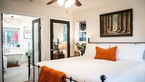 Een slaapkamer met een groot bed, een plafondventilator en een schilderij aan de muur.
