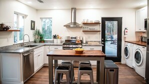 Een moderne keuken met een centraal eiland, roestvrijstalen apparatuur en uitzicht op buiten.