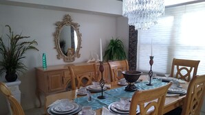 A dining room with a wooden table set for four, surrounded by chairs. A large mirror hangs on the wall above the table. - Book this home for a relaxing vacation in Rotonda West! (Rotonda West)