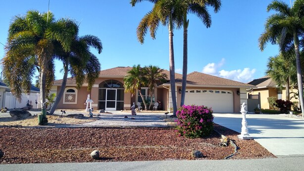 A residential house with a garage, palm trees, and a driveway. - Book this home for a relaxing vacation in Rotonda West! (Rotonda West)