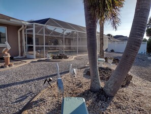A house with a covered patio, palm trees, and decorative bird sculptures.