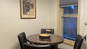 Un comedor con una mesa redonda, cuatro sillas y un cuadro en la pared.