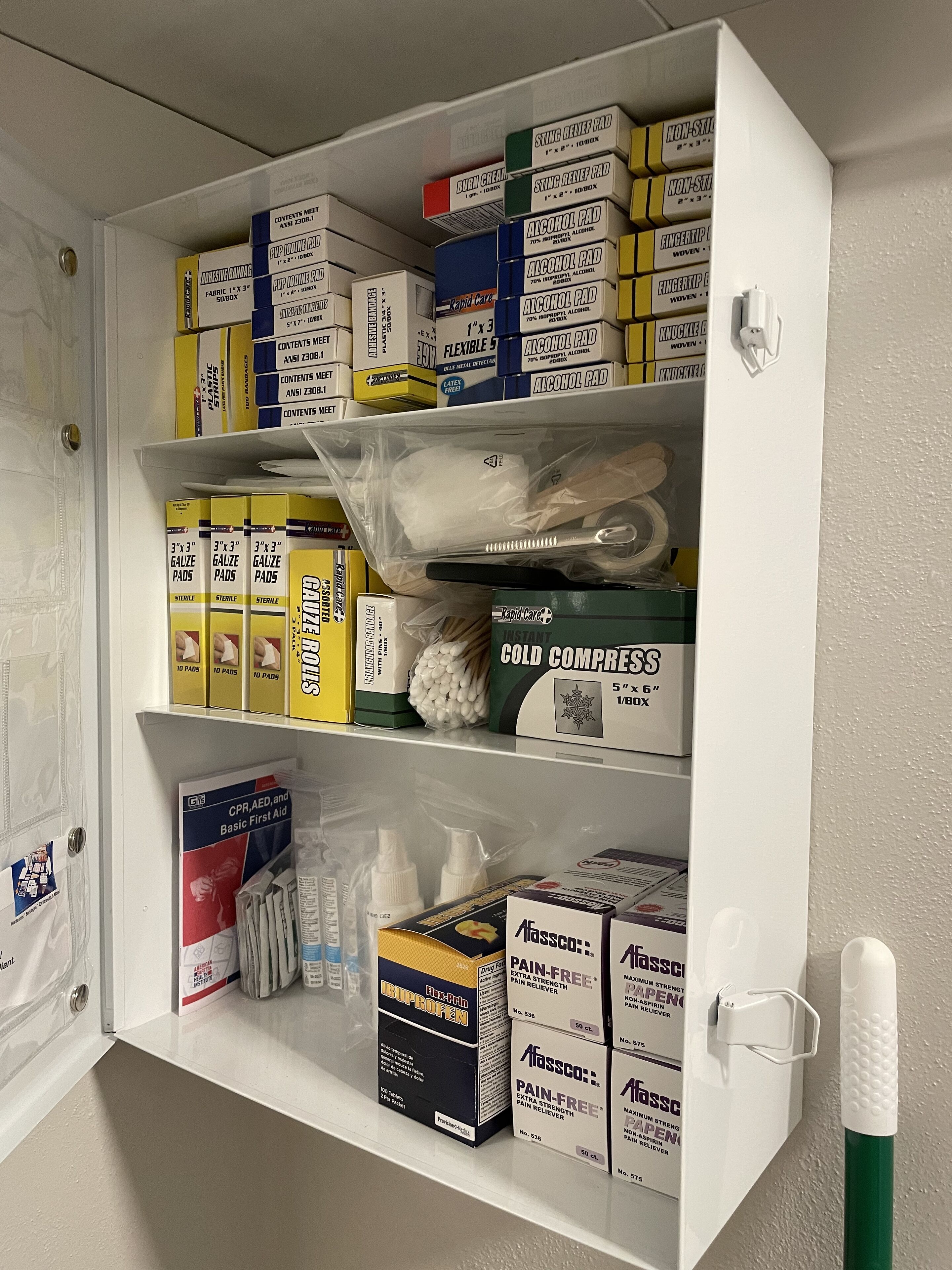 Une armoire médicale contenant divers articles de premiers secours, notamment une crème pour les brûlures, des compresses imbibées d’alcool, des compresses de gaze et des analgésiques.