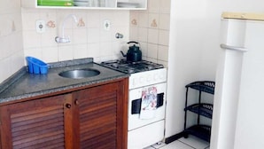 Une cuisine de taille réduite, équipée d’un évier, d’une cuisinière et de placards.