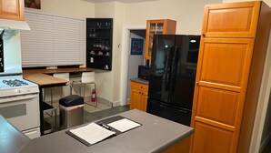A compact kitchen with a stove, refrigerator, and wooden cabinets. - Olympic Hills six bed haven with hot tub and grill (Seattle)