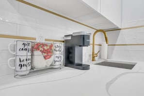 A modern kitchen with a coffee machine, a heart-shaped decoration, and motivational mugs.