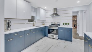 Une cuisine moderne avec des armoires bleues, une cuisinière en acier inoxydable et un sol en marbre.