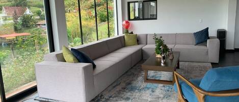 A modern living room with a large sectional sofa, a coffee table, and a blue armchair.