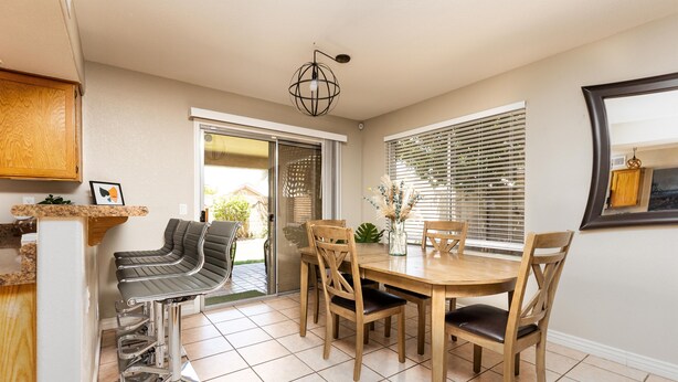 A dining area with a wooden table and chairs, a bar stool, and a ceiling light fixture. - Walk to Stadium|Westgate|Glendale (Glendale)