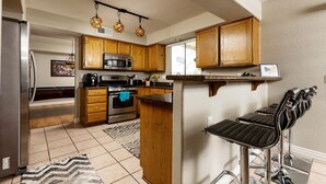 A kitchen with wooden cabinets, a stainless steel refrigerator, a microwave, and a coffee maker. - Walk to Stadium|Westgate|Glendale (Glendale)