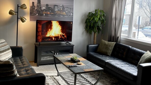 Ein Wohnzimmer mit Kamin, einer Couch, einem Couchtisch und einem Stadtbildgemälde.