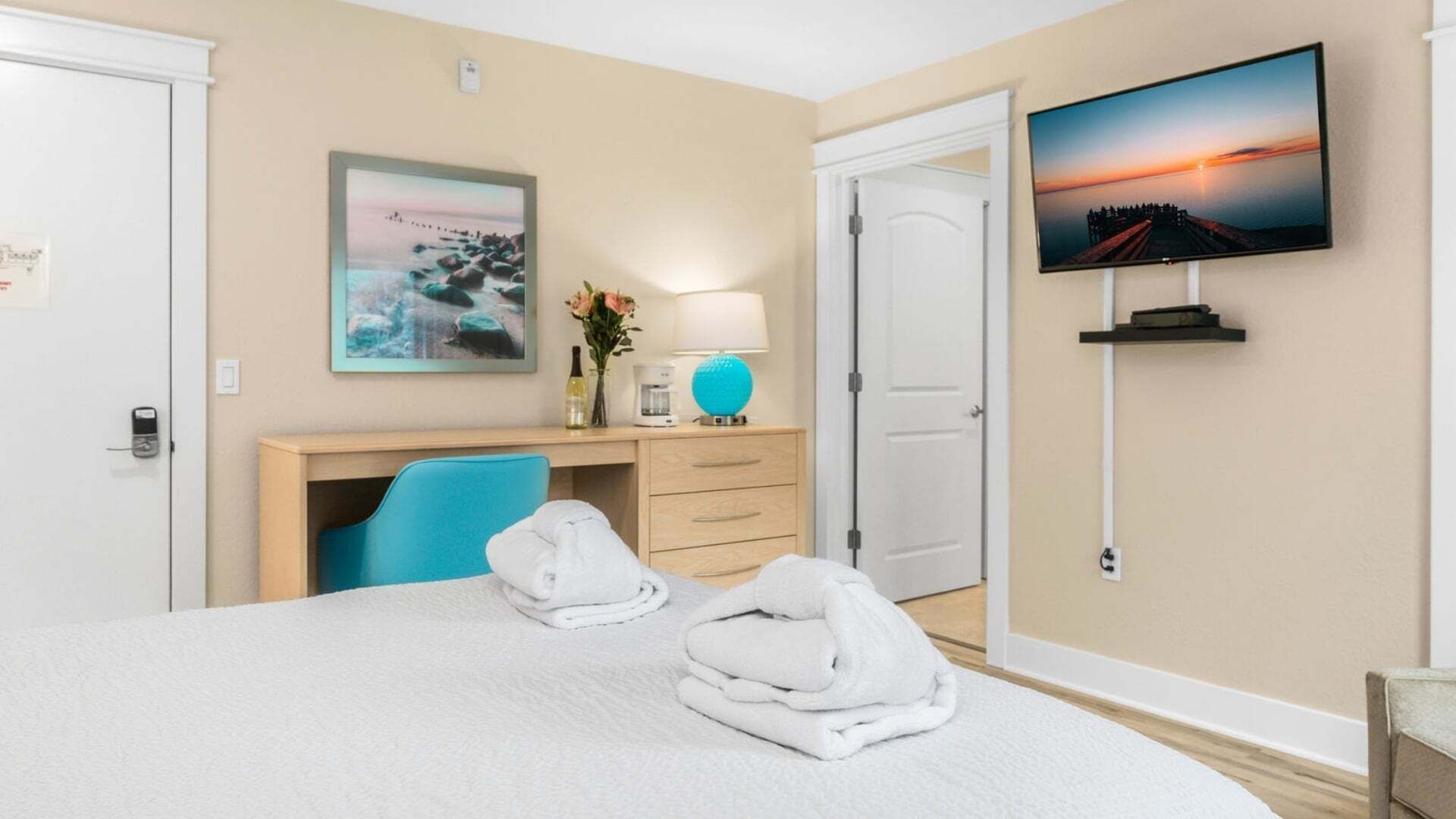 Une chambre d’hôtel avec un lit, un bureau, une chaise, une télévision et un tableau au mur.