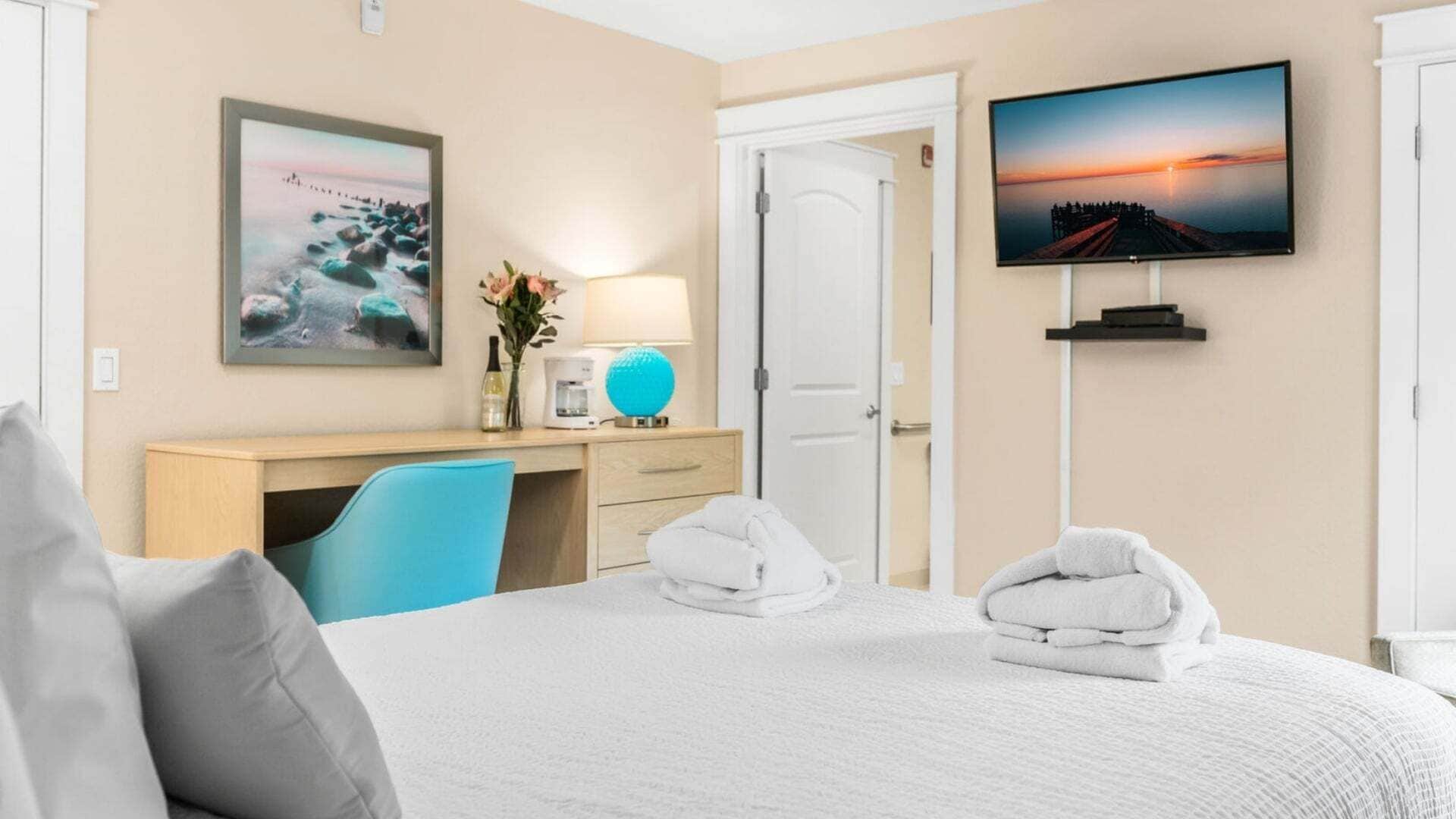 Ein Hotelzimmer mit Bett, Schreibtisch, Stuhl, Fernseher und einer Tür.
