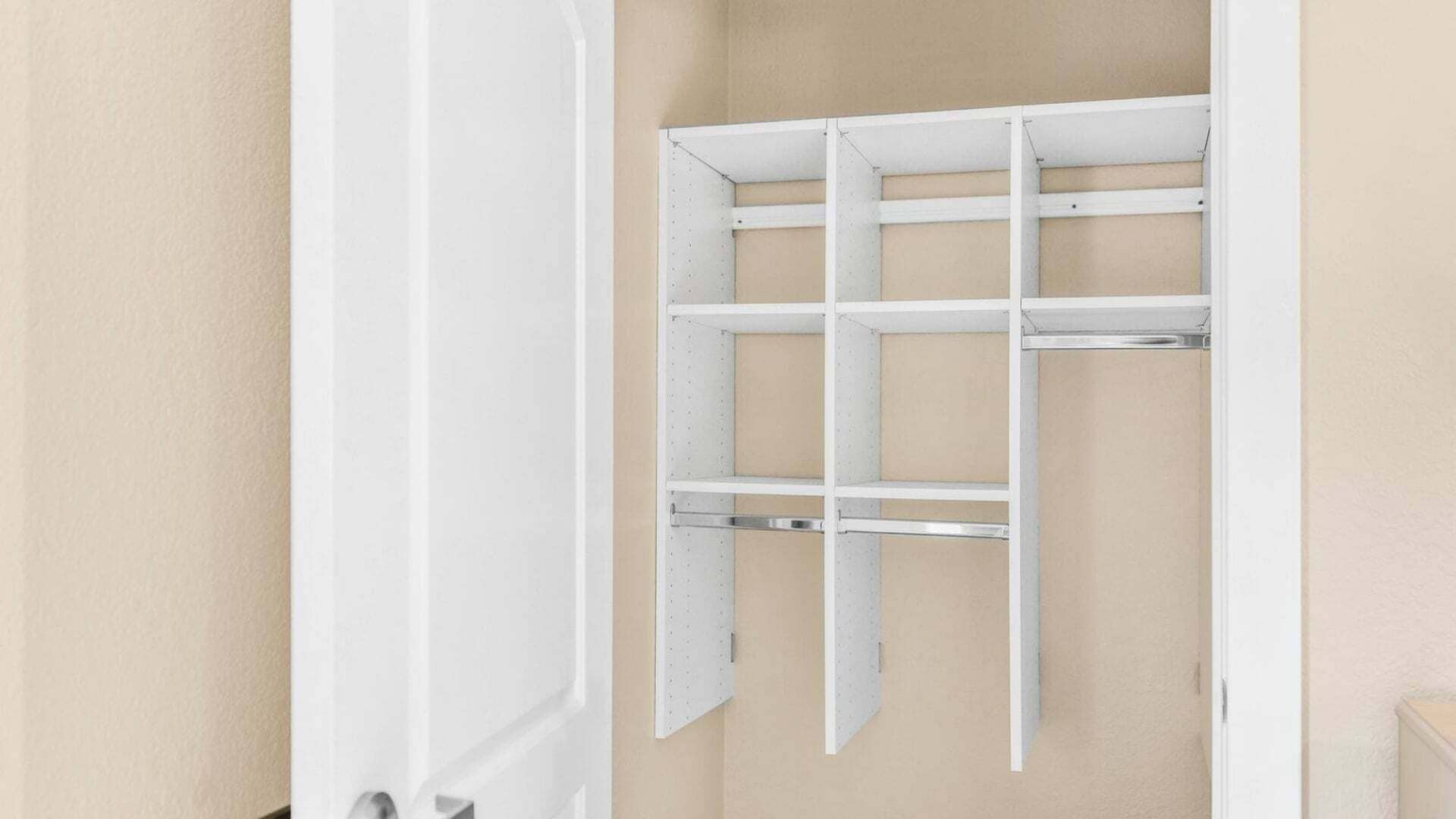 Une porte blanche, un mur de couleur beige et une étagère blanche comportant plusieurs compartiments.