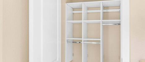 Une porte blanche, un mur de couleur beige et une étagère blanche comportant plusieurs compartiments.