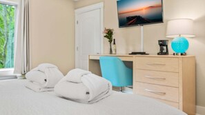 Une chambre d’hôtel équipée d’un lit, d’un bureau, d’une chaise, d’un téléviseur fixé au mur et d’une lampe.
