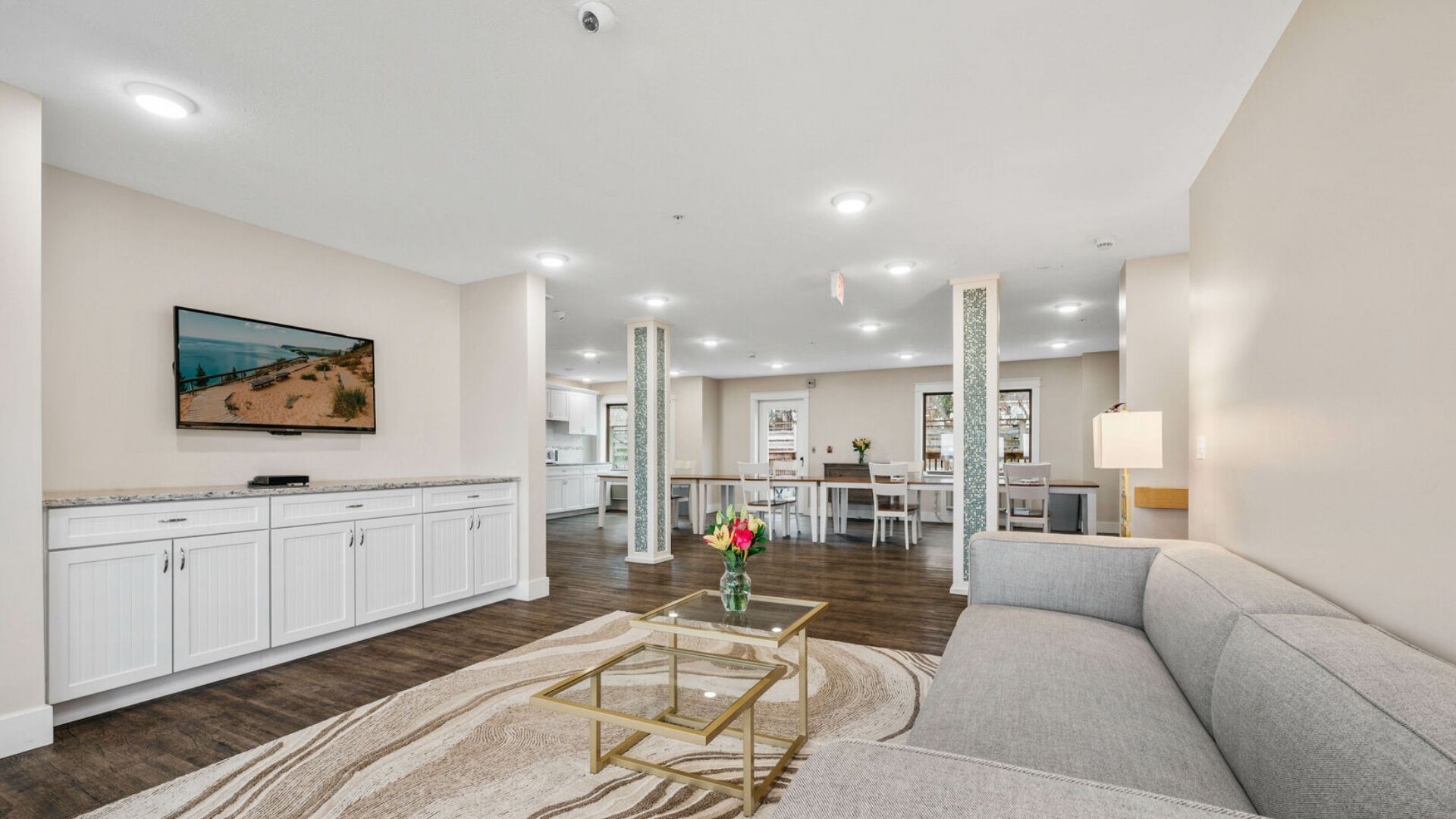 A spacious living area with a sofa, a coffee table, and a television mounted on the wall.