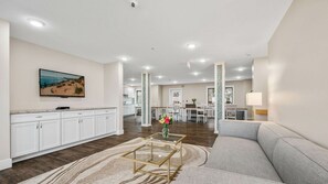 A spacious living area with a sofa, a coffee table, and a television mounted on the wall.