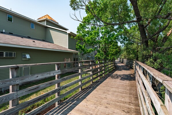 A wooden boardwalk leading to a building with a sloped roof and a small window.