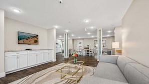 A spacious living area with a sofa, a coffee table, and a kitchen in the background.