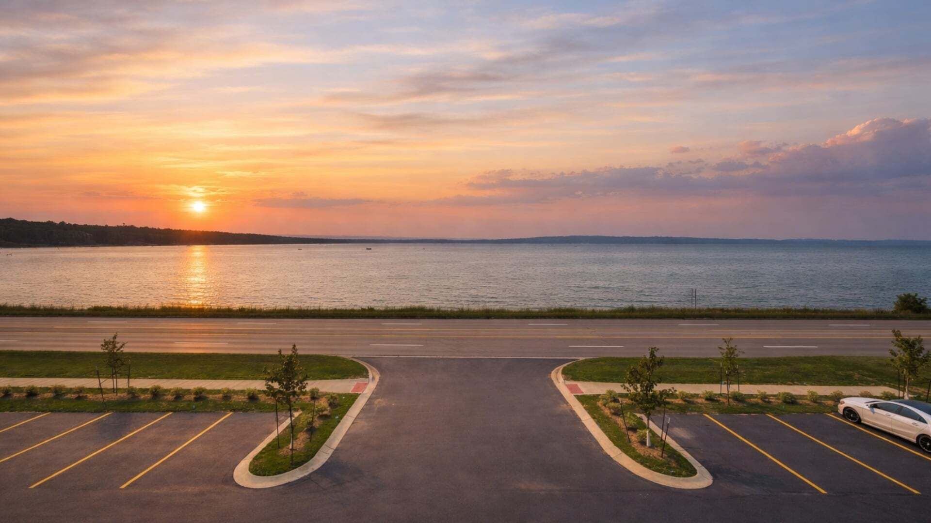 Un parking offrant une vue sur un coucher de soleil se reflétant sur une étendue d’eau.