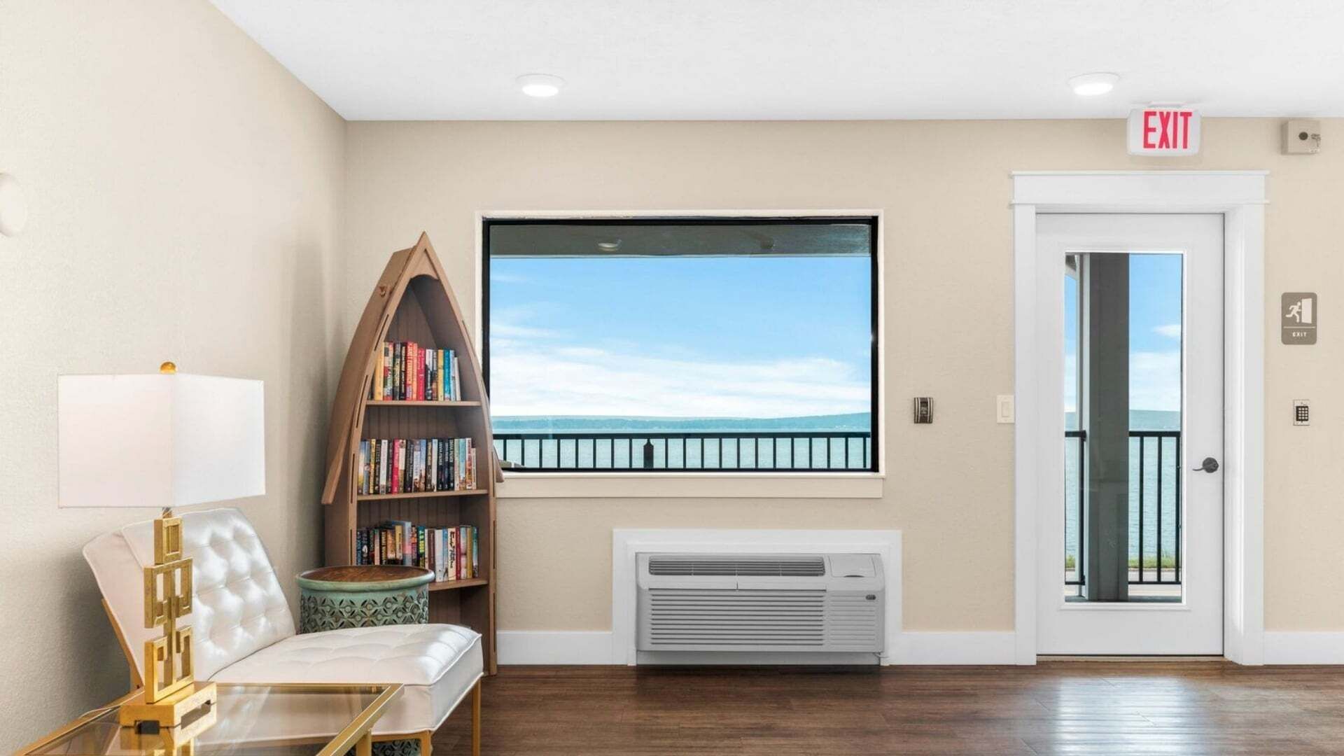 Een hotel lobby met een groot raam, een boekenkast, een bank en een airconditioning.