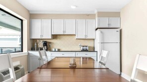 Eine moderne Küche mit weißen Schränken, einem Holzespeisetisch und einem Kühlschrank.