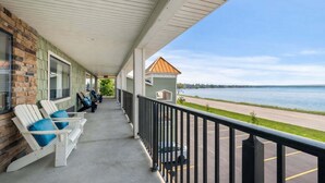 A covered porch with seating, a view of a body of water, and a parking lot.