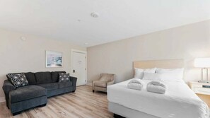 Une chambre d’hôtel avec un lit, un canapé, une chaise et une table de chevet.