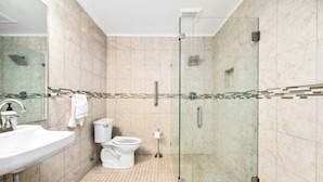A modern bathroom with a glass-enclosed shower, a white sink, and a toilet. - 🏖️ Gold Coast Inn | Breathtaking Sunsets • Deluxe Garden View Room 109 (Traverse City)