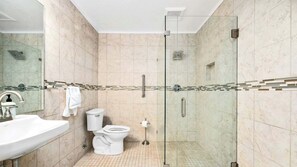Een moderne badkamer met een glazen douchecabine, een wit wastafelmeubel en een toilet.