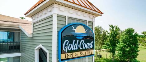 A building with a sign for 'Gold Coast Inn & Suites' featuring a sunset and seagulls.