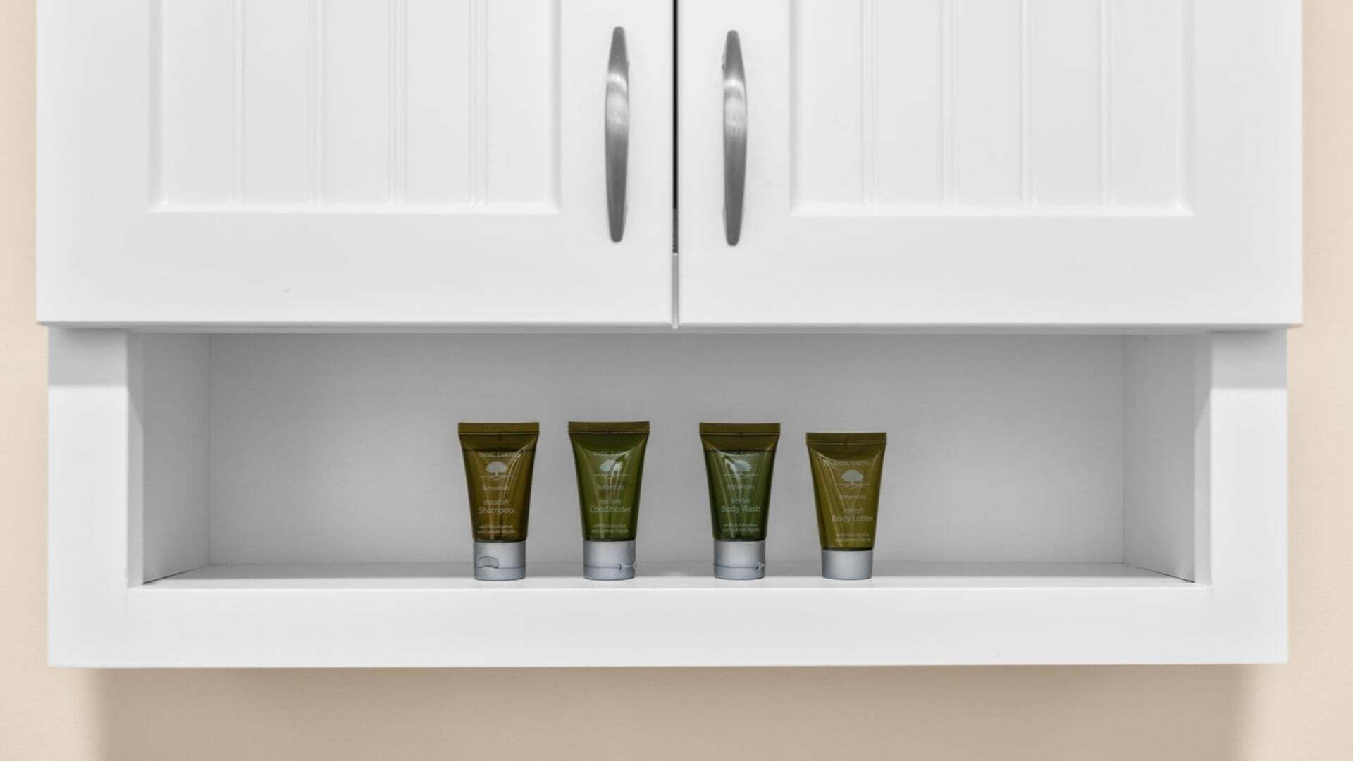 A white cabinet with a shelf containing four tubes of body wash.