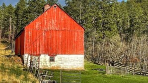 A red barn with a white lower section, surrounded by a grassy field and trees, under a partly cloudy sky with a visible rainbow. - Nemo Farmhouse on Centennial Trail With a View (Nemo)