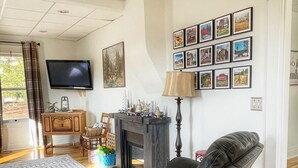 A living room with a fireplace, a sofa, a television, and a wall with framed pictures. - Nemo Farmhouse on Centennial Trail With a View (Nemo)