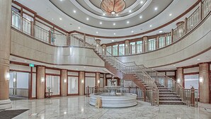Un vestíbulo espacioso con una fuente central, varias escaleras y un gran candelabro.
