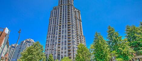 Un grand immeuble moderne, doté de nombreux balcons, entouré d’arbres et agrémenté d’un jardin bien entretenu.