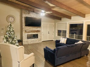 A living room with a fireplace, a Christmas tree, a sofa, and a television.