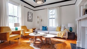 Una sala de estar con un sofá, dos sillones, una mesa de centro y una alfombra.